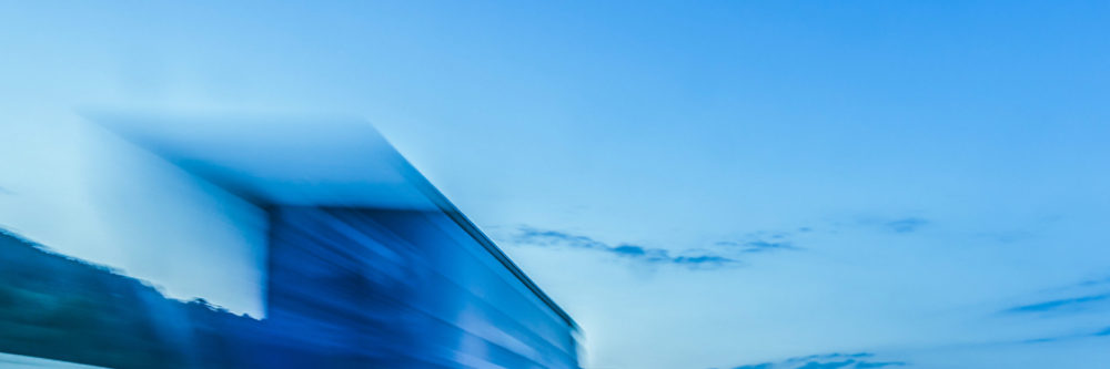 Background photograph of a highway. Truck on a motorway, motion blur, light trails. Evening or night shot of trucks doing logistics and transportation on a highway.